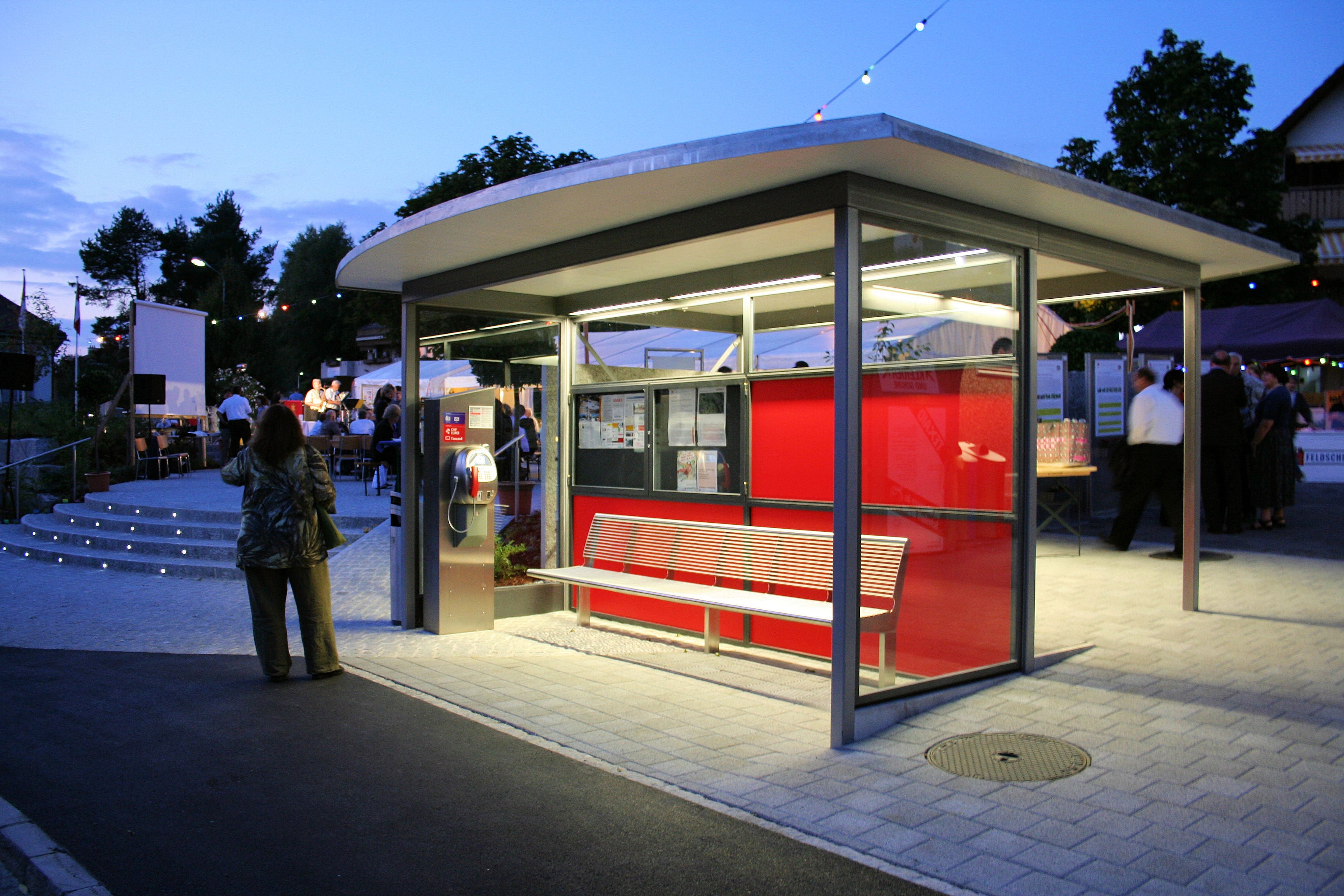 2009 wurde im Zuge der Realisierung des Dorfplatzes samt Altstoffsammelstelle mit unterirdischem Entsorgungssystem auch die gedeckte Bushaltestelle ersetzt und der bergseitige Warteraum mit einem Velounterstand ergänzt. Bild: Einweihungsfest Dorfplatz vom 22.08.2009/Walter Bürgi