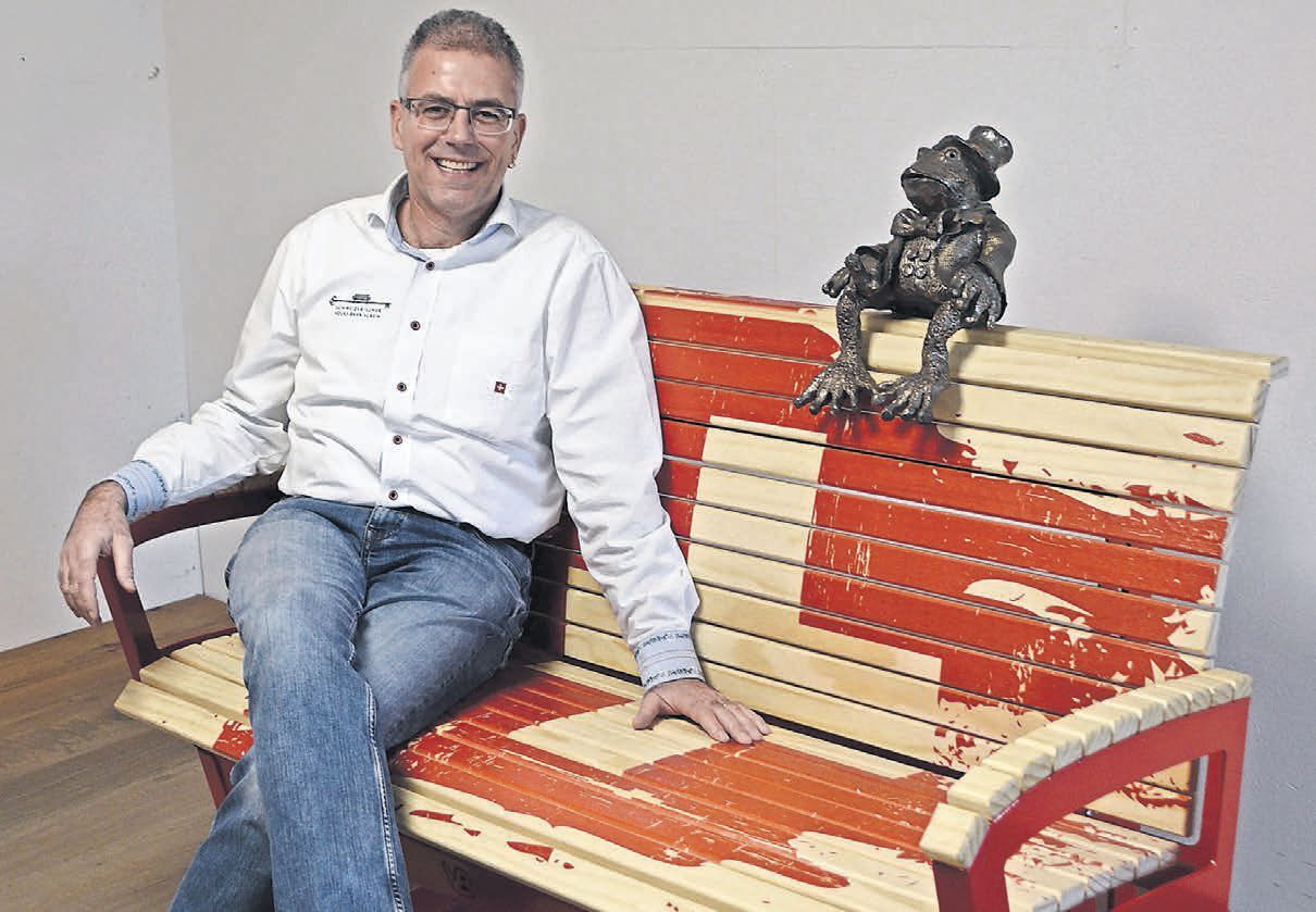 Die Freude über seine «perfekte» Sitzbank ist Paul Wertli anzusehen. «Ich bin zwar der ‹Bank-Papi› – aber Kurt Bankrott ist der Bankrat. Er kennt sich aus mit den Kröten», meint Wertli lächelnd und zeigt auf die Kröten-Skulptur neben ihm. Bild: BBA 12.04.2024/Sabrina Salm