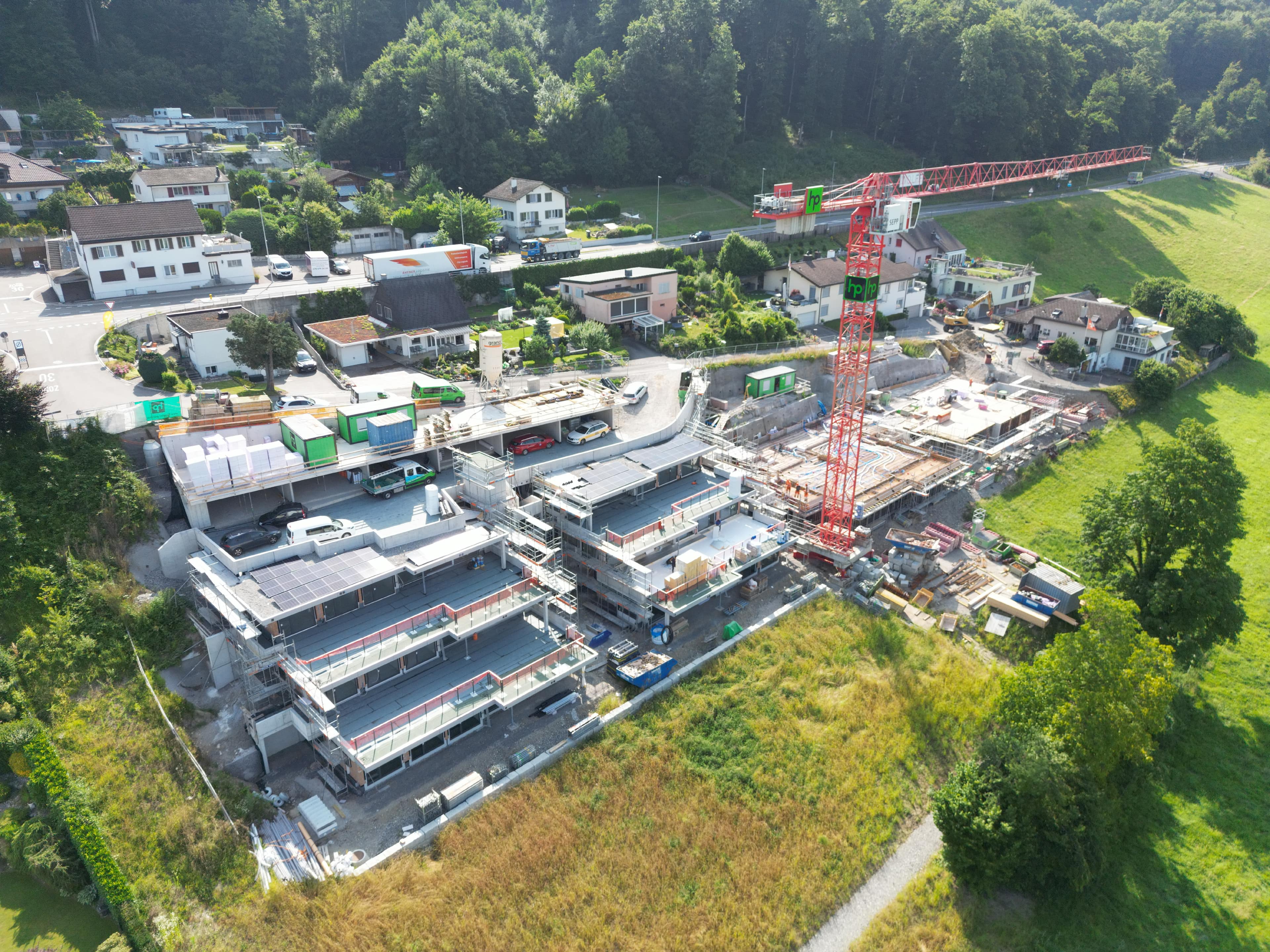 Im März 2024 erteilte der Gemeinderat der Zürcher Immobilien Plus AG mit Rechtsdomizil in Zufikon die Baubewilligung für den Neubau von 10 Terrassenhäusern in der Erlismatt Eggenwil mit 2 Parkdecks inklusive PV-Anlagen auf den Parzellen Nrn. 102 und 103, Erlismattweg 2 bis 20, den Rückbau von Gebäude Nr. 163 des stillgelegten Quellwasserpumpwerks Erlismatt samt Zufahrtsstrasse mit Ersatz der öffentlichen Fusswegverbindung zwischen Erlismattweg und Reussebene auf Parzelle Nr. 103 sowie die Offenlegung und Reaktivierung des öffentlichen Gewässers samt neuer Hecke «Ausserfeldgraben» auf Parzelle Nr. 102. Der Baubeginn erfolgte Ende April 2024. Inzwischen wurde der Rohbau der 1. Etappe weitgehend abgeschlossen und die 2. Etappe ist in vollem Gange. Es wird davon ausgegangen, dass die Hochbauten bis kommenden Frühling realisiert sein werden, sodass danach durch die Gemeinde die ebenfalls im März 2024 baubewilligte Sanierung des Erlismattwegs in Angriff genommen werden kann. Drohnenbild: Architekt Alex Müller/23.06.2025